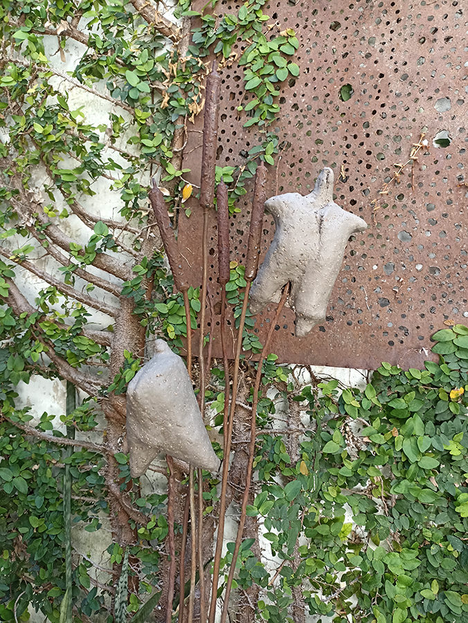 Ungebrannte weibliche Tonfiguren hängen zum Trocknen im Garten