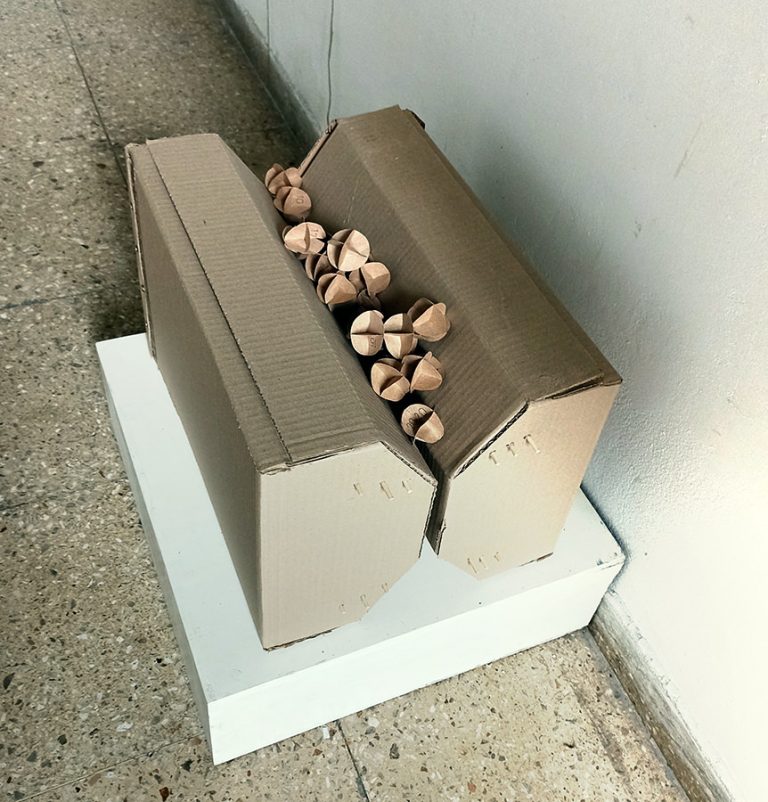 Objekt aus KArton in dem ein Haufen kleiner Kartonkugeln liegen